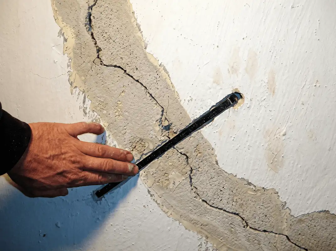 A wall with a large crack is being inspected by a professional in Arlington, TX